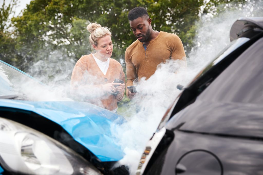 Two Motorists Swapping Insurance Details On Mobile Phone After Car Crash